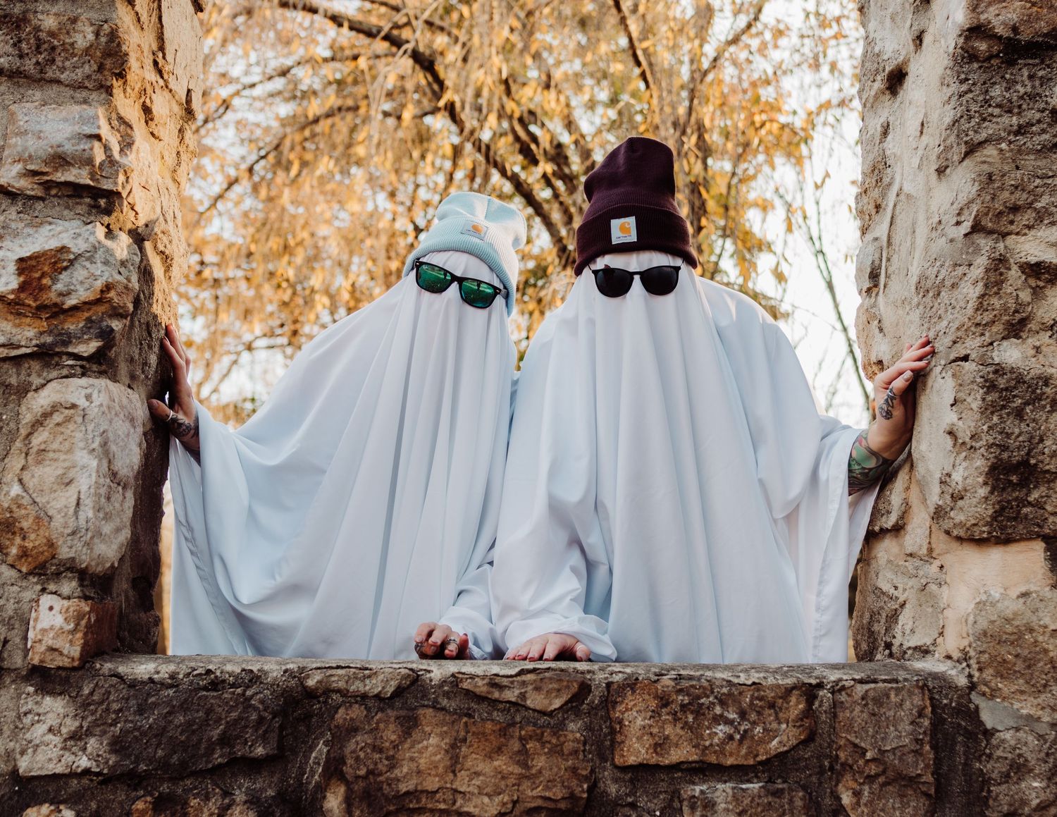 White-sheeted figures create spooky poses along historic stone wall architecture.