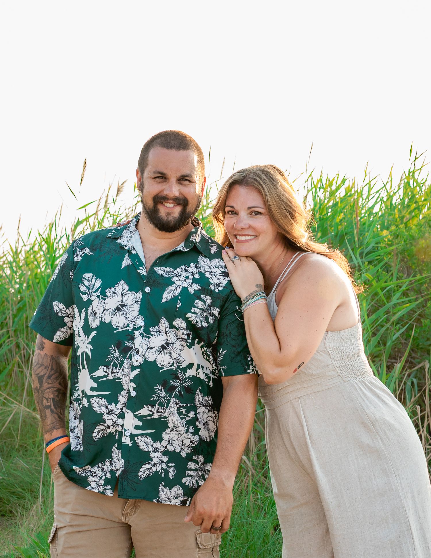 A couple shares joyful moments together outdoors among tall grass in a series of casual engagement photos.