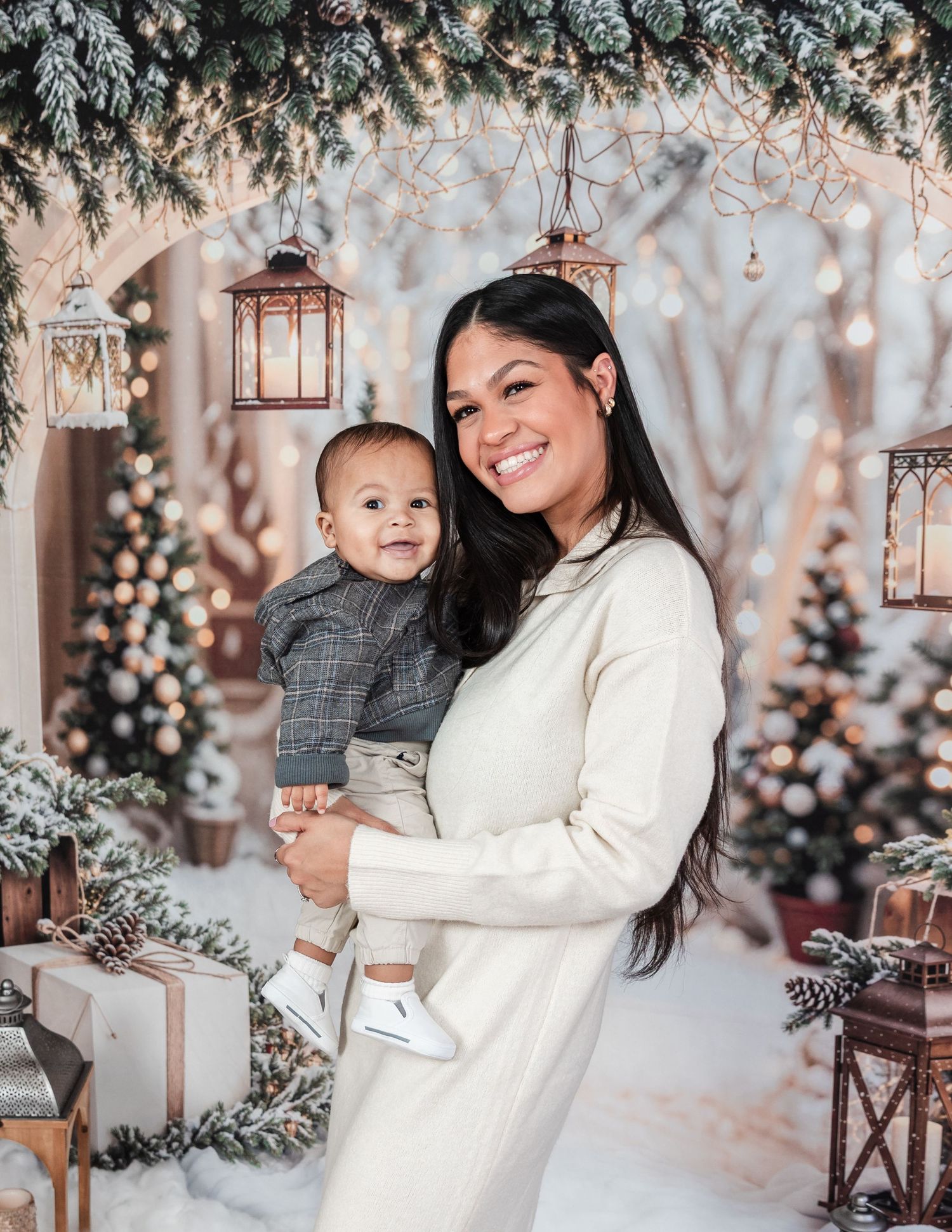 Cozy winter family photoshoot with snow-covered trees and hanging lanterns creating magical atmosphere.