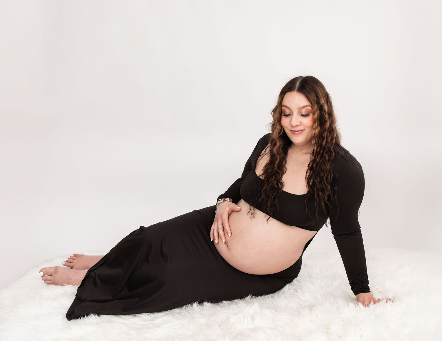 Artistic maternity portraits with woman in black dress on white background.