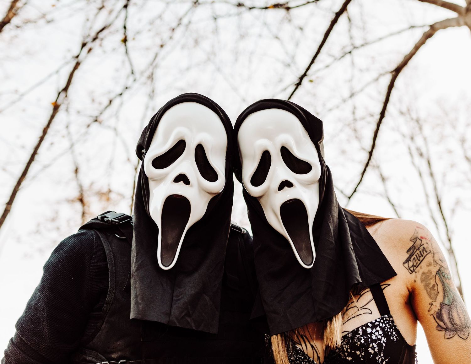 Multiple ghostface masks lined up against a white winter sky background.