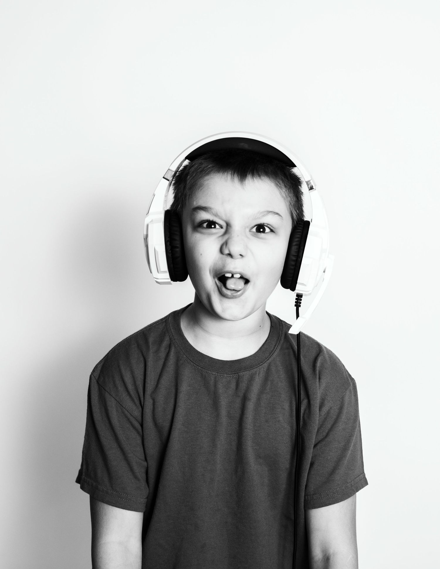 A black and white portrait of someone wearing white headphones with an excited expression.