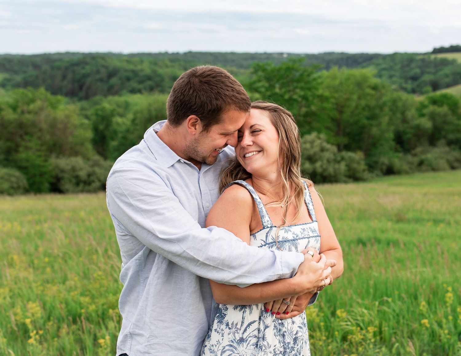Intimate embrace between couple in flowering spring meadow with rolling hills.