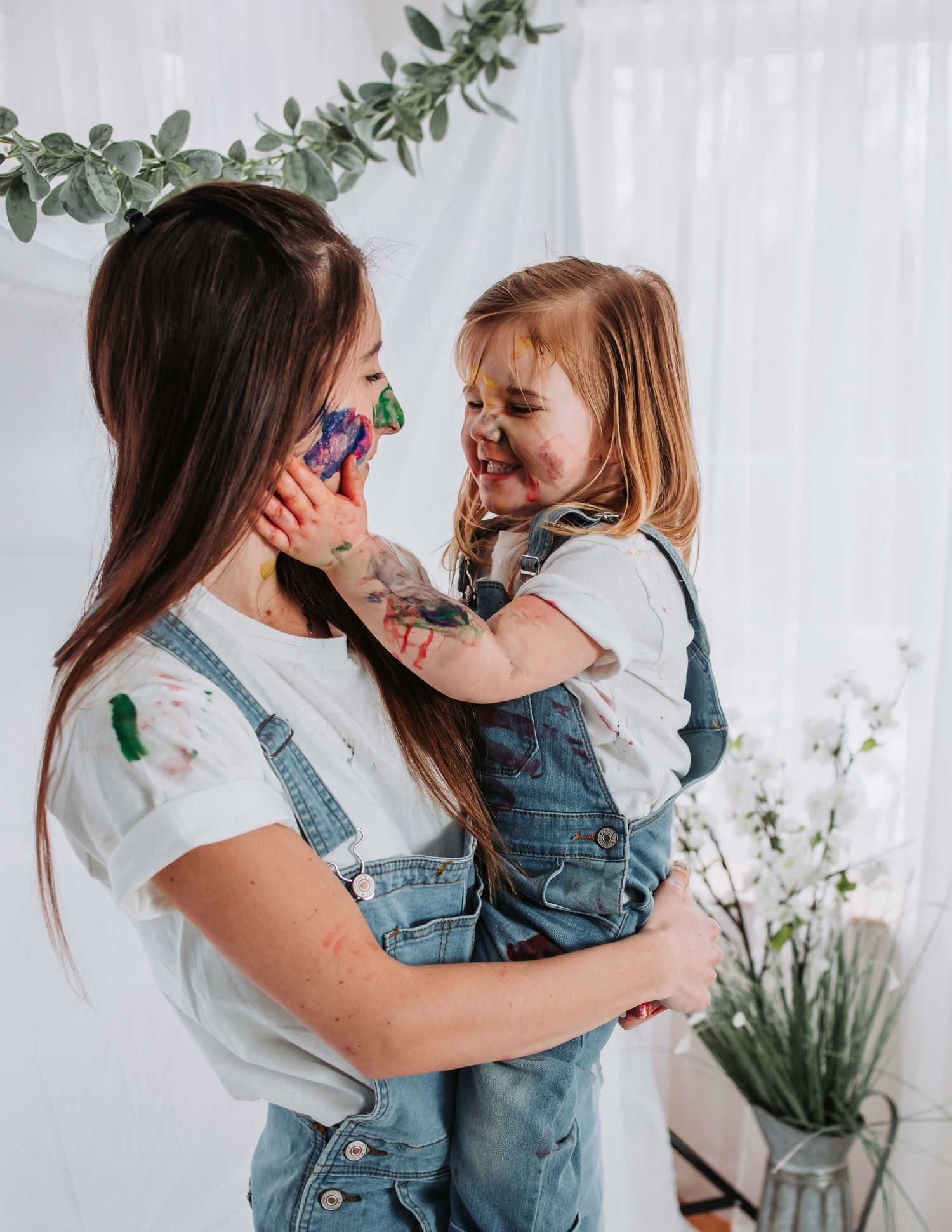 Paint-covered faces share joyful moments during creative art time.