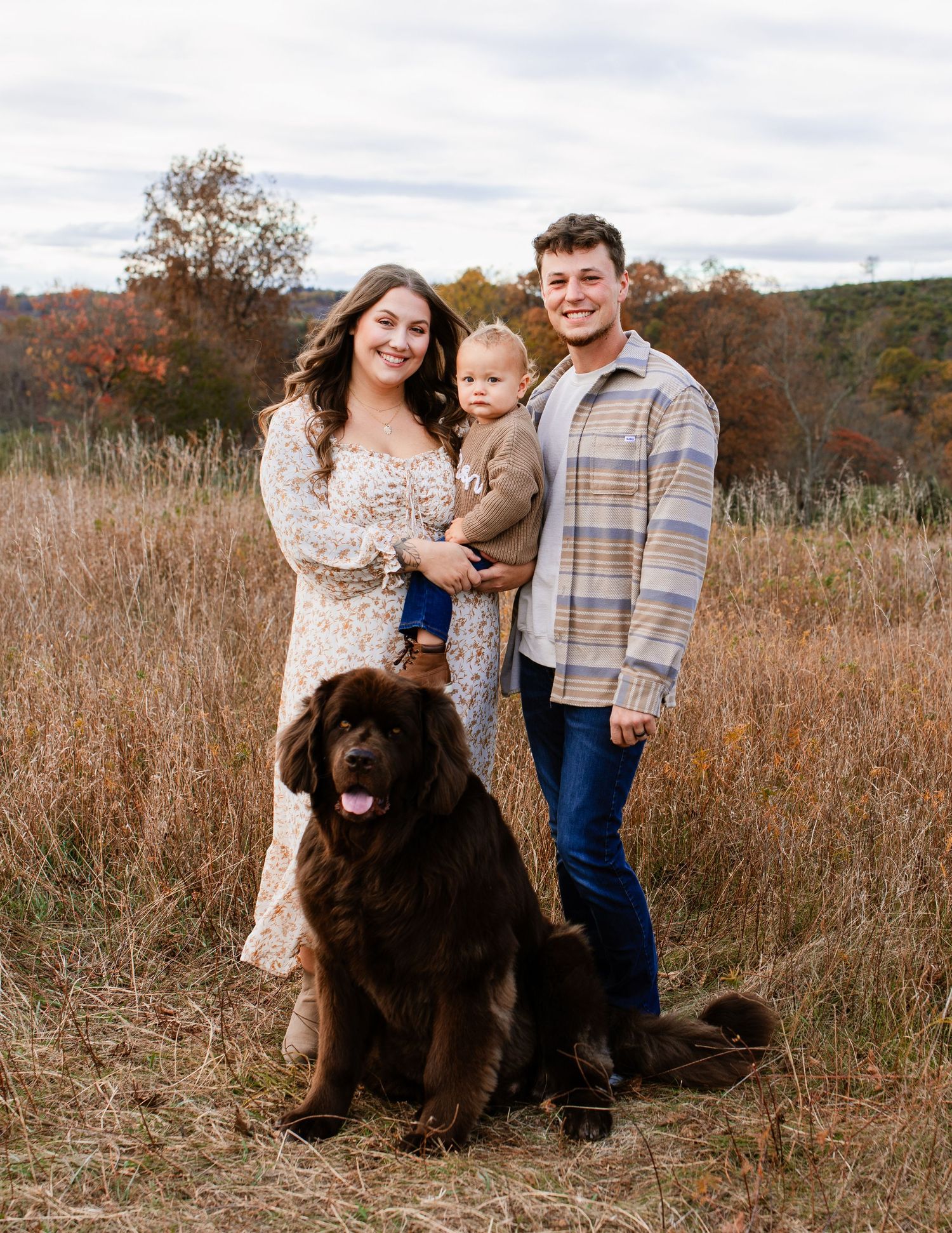 Family portrait with chocolate lab dog in an autumn field with dried grass.