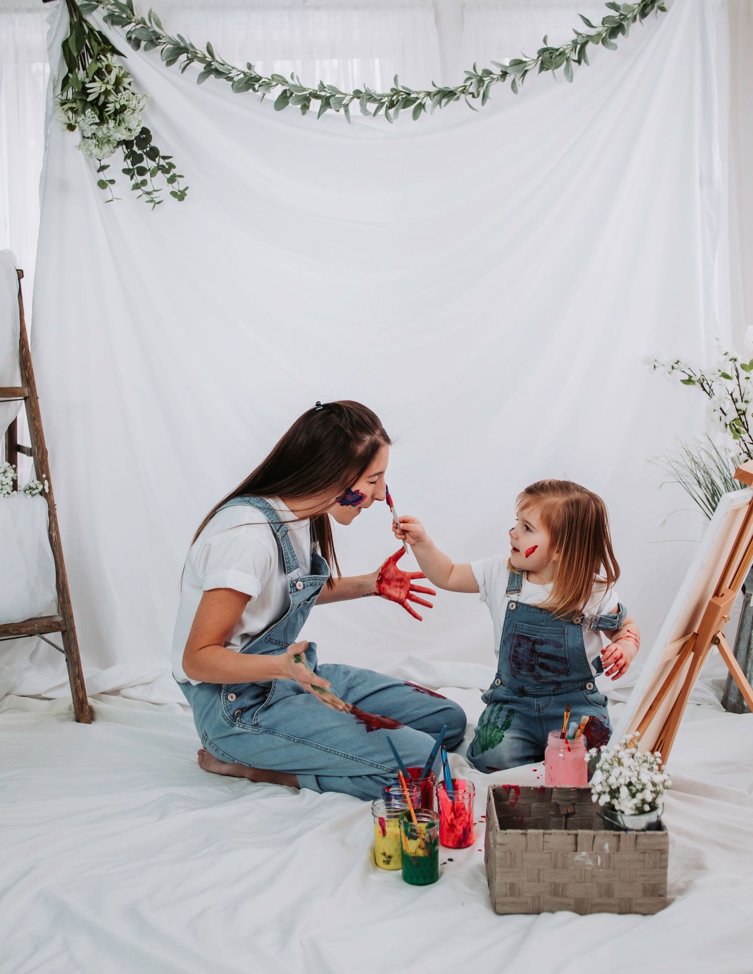 Parent and child sharing messy paint play moments on white background.