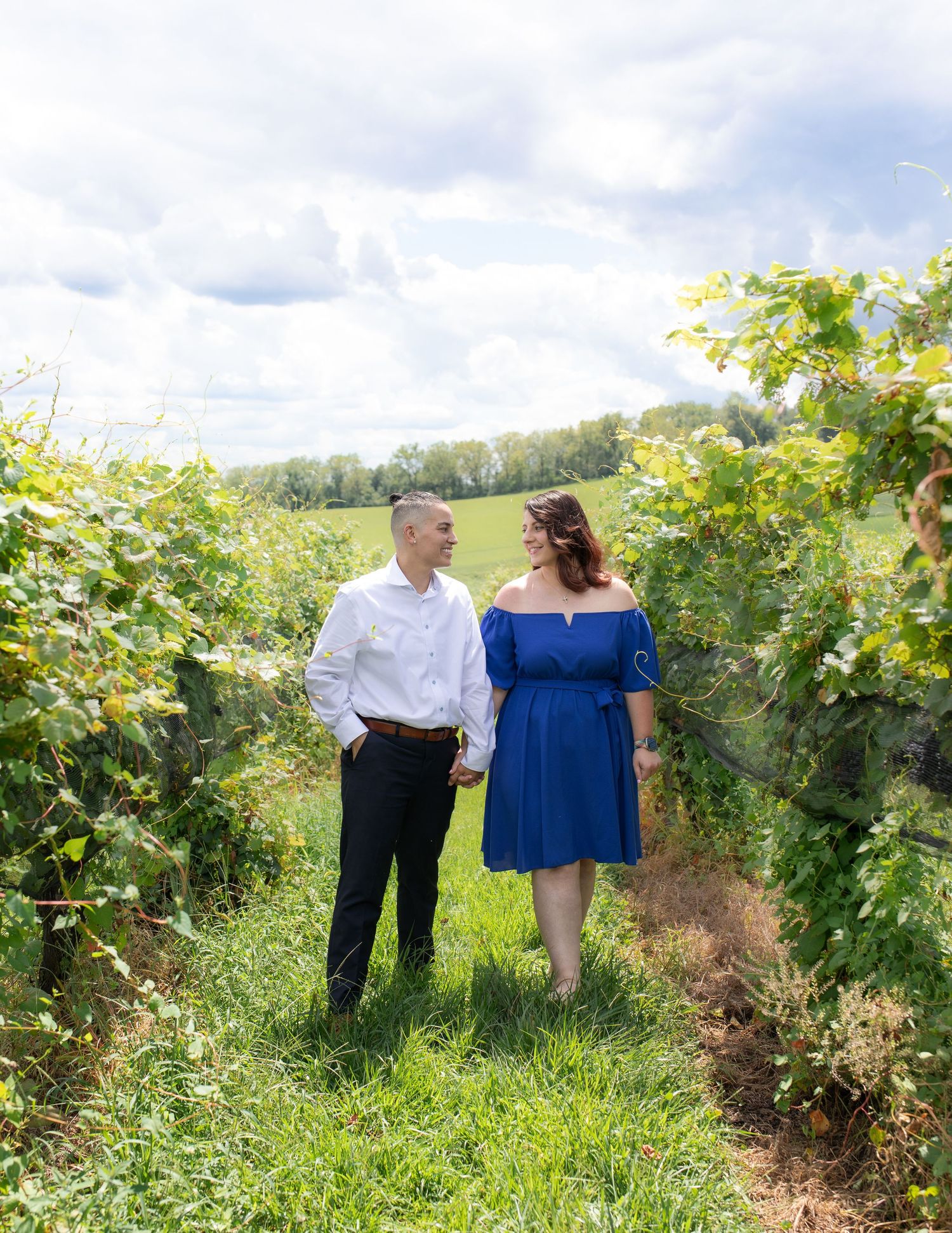 Couple sharing intimate moments among vineyard rows on a bright summer day.
