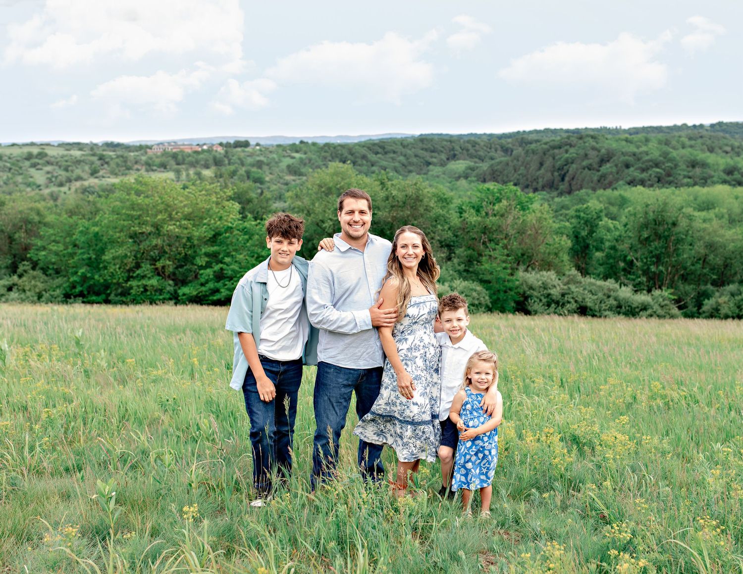 Family walking together through a scenic green meadow on a spring day.