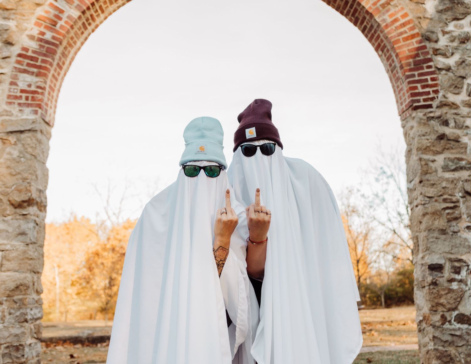 Ghost figures in white sheets pose dramatically against brick and stone archways.