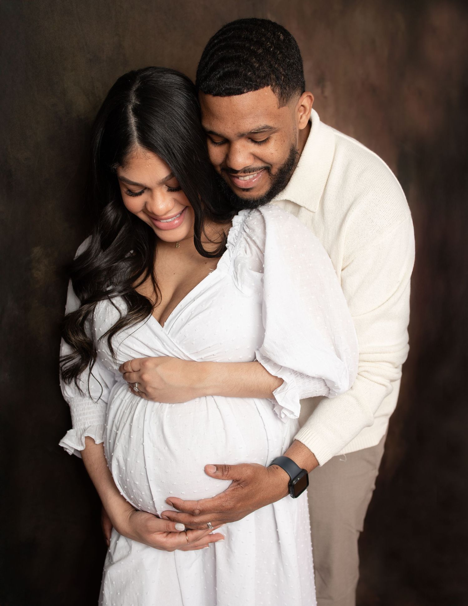 Intimate maternity photography session with couple in coordinating white outfits.