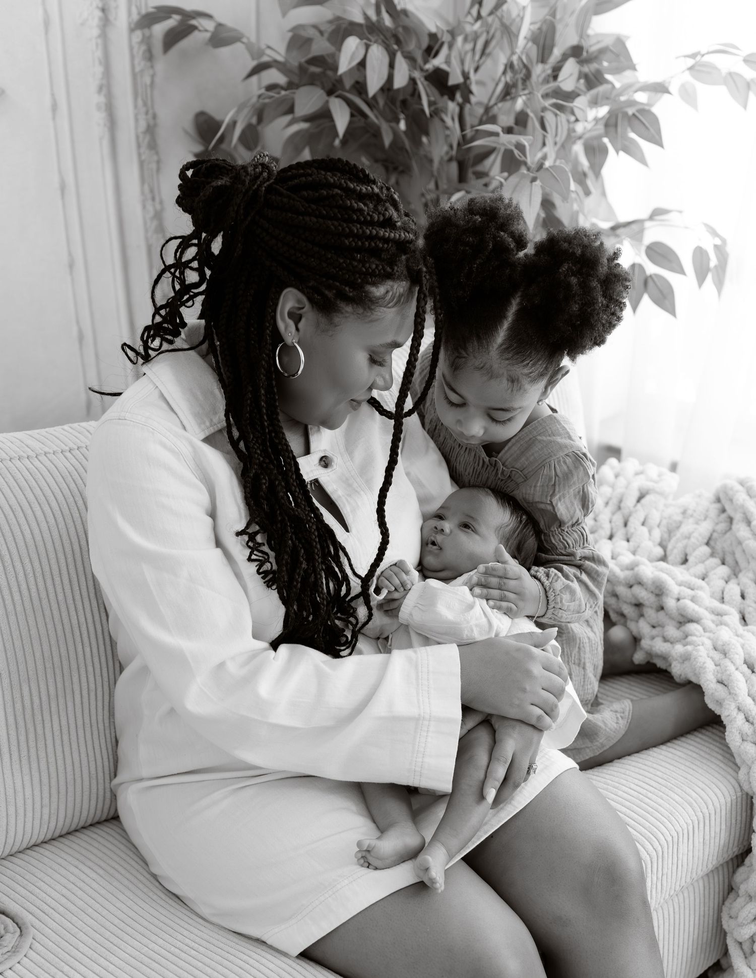 Black and white photo series showing tender moments between a parent and child on a white couch.