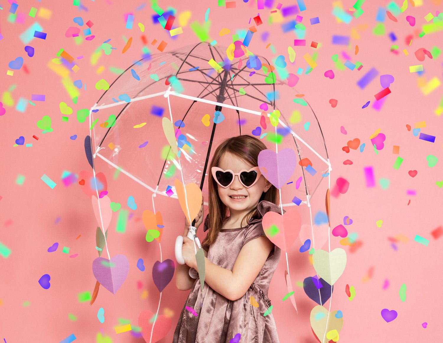Playful scene with pink umbrella and colorful confetti against pink background.