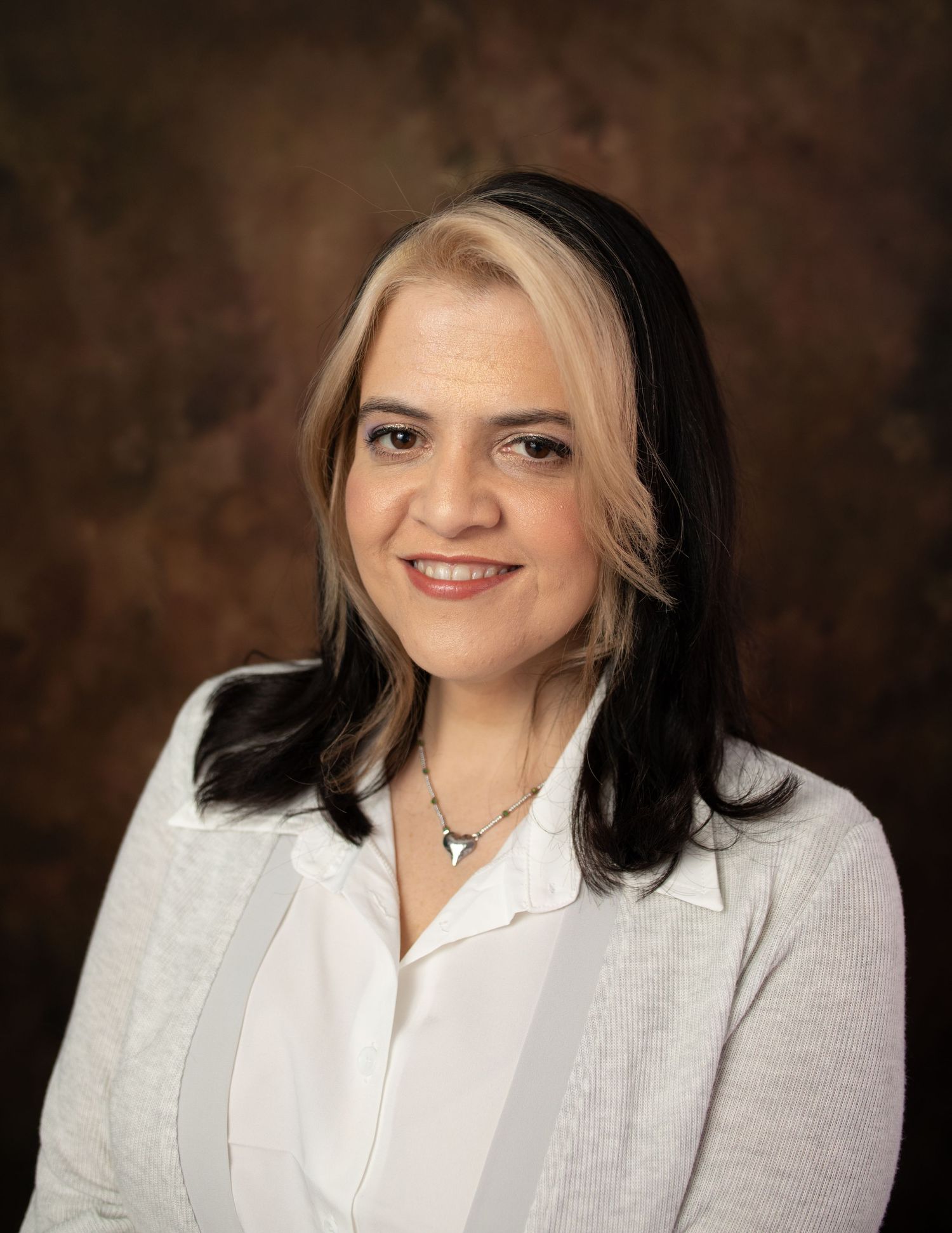 Professional headshot against brown background with two-toned hair.