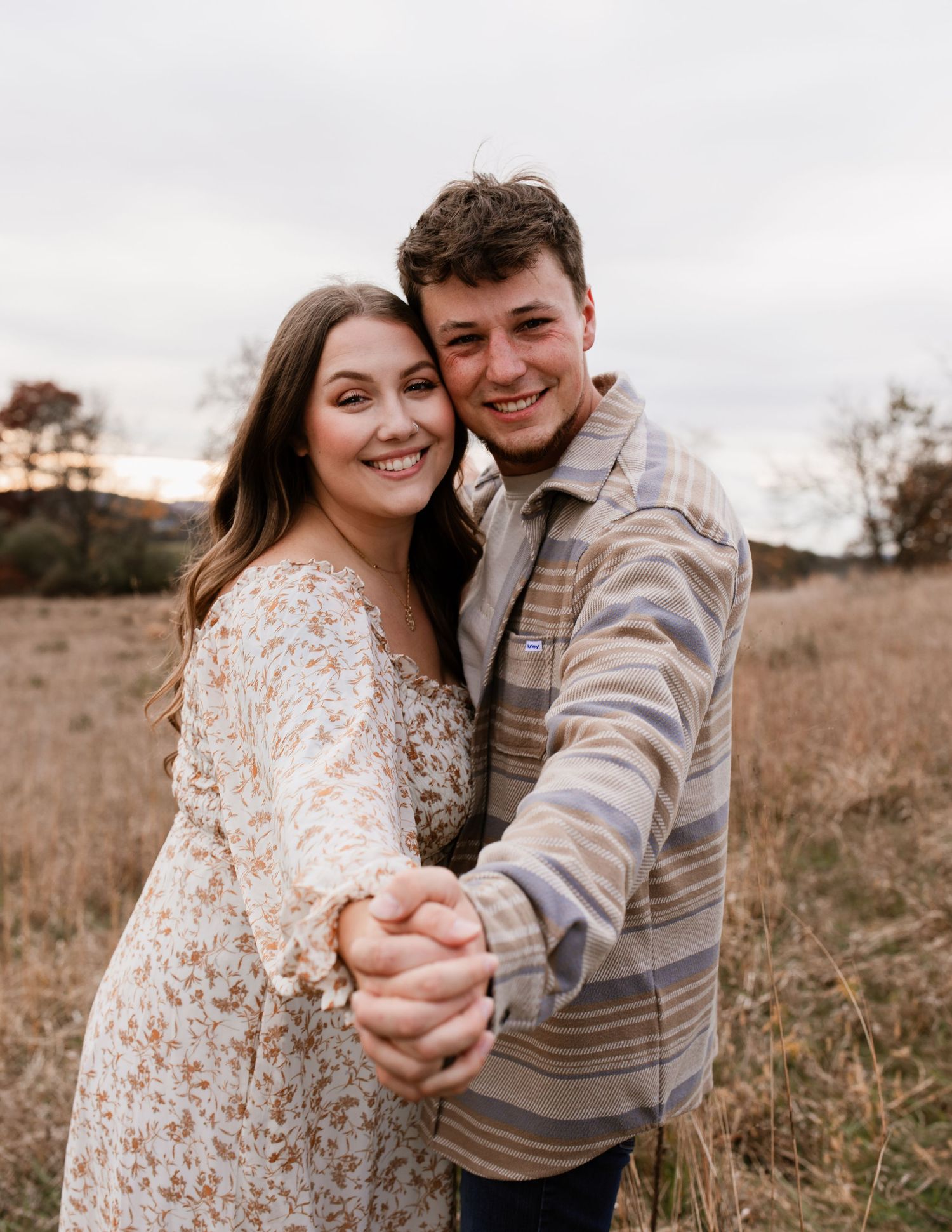 Couple dancing and embracing in a golden autumn field during sunset.