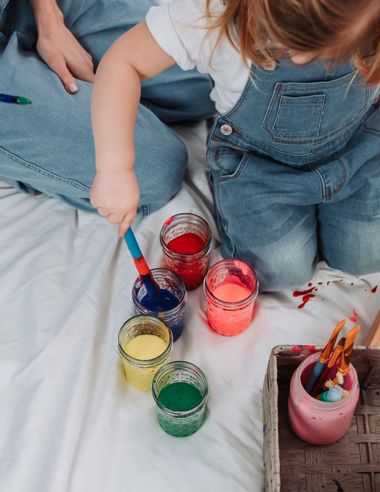 Colorful paint jars arranged on white surface during art activity.