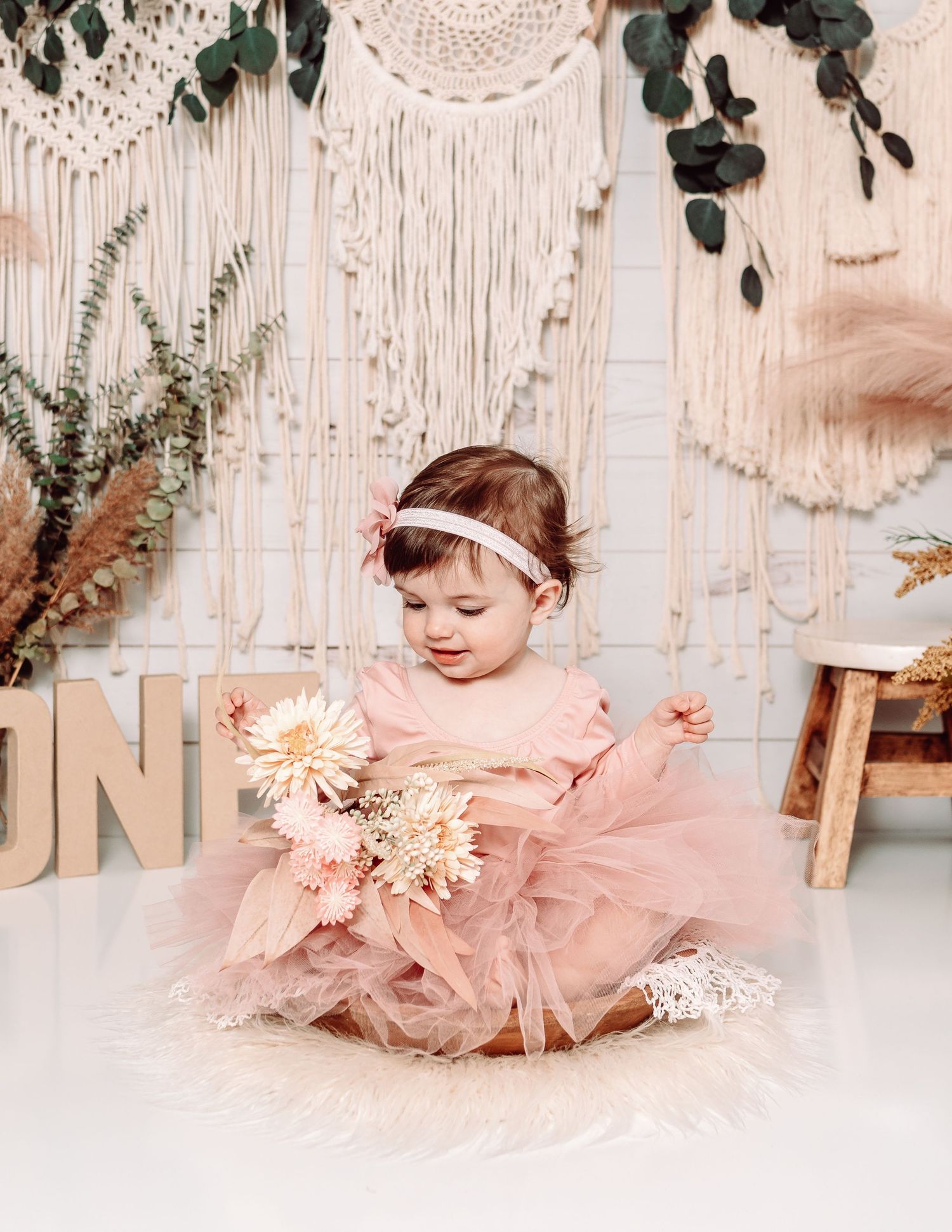 Boho-style cake smash setup with macrame backdrop and pink tulle dress details.