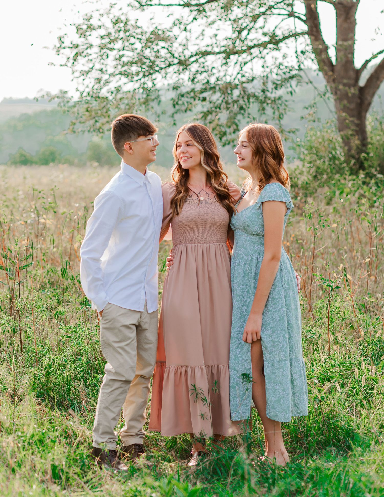 Casual family photo session in a meadow with everyone wearing coordinated pastel colors.