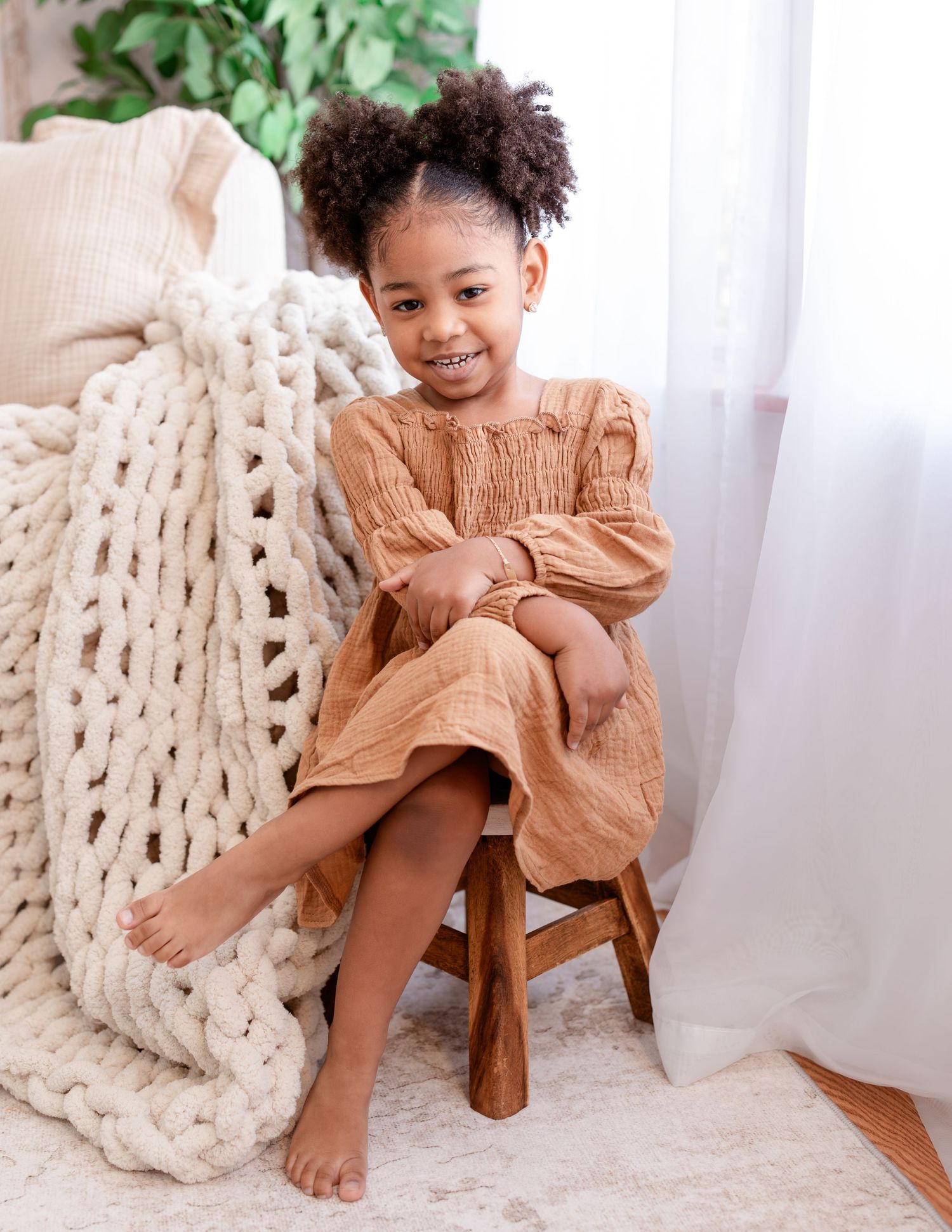 Cozy interior scene with chunky knit blanket and wooden stool near bright window with natural light.