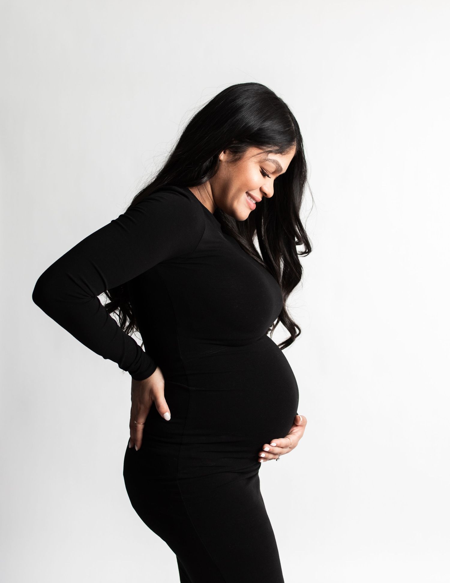 Silhouette of pregnant woman in black dress against white background.