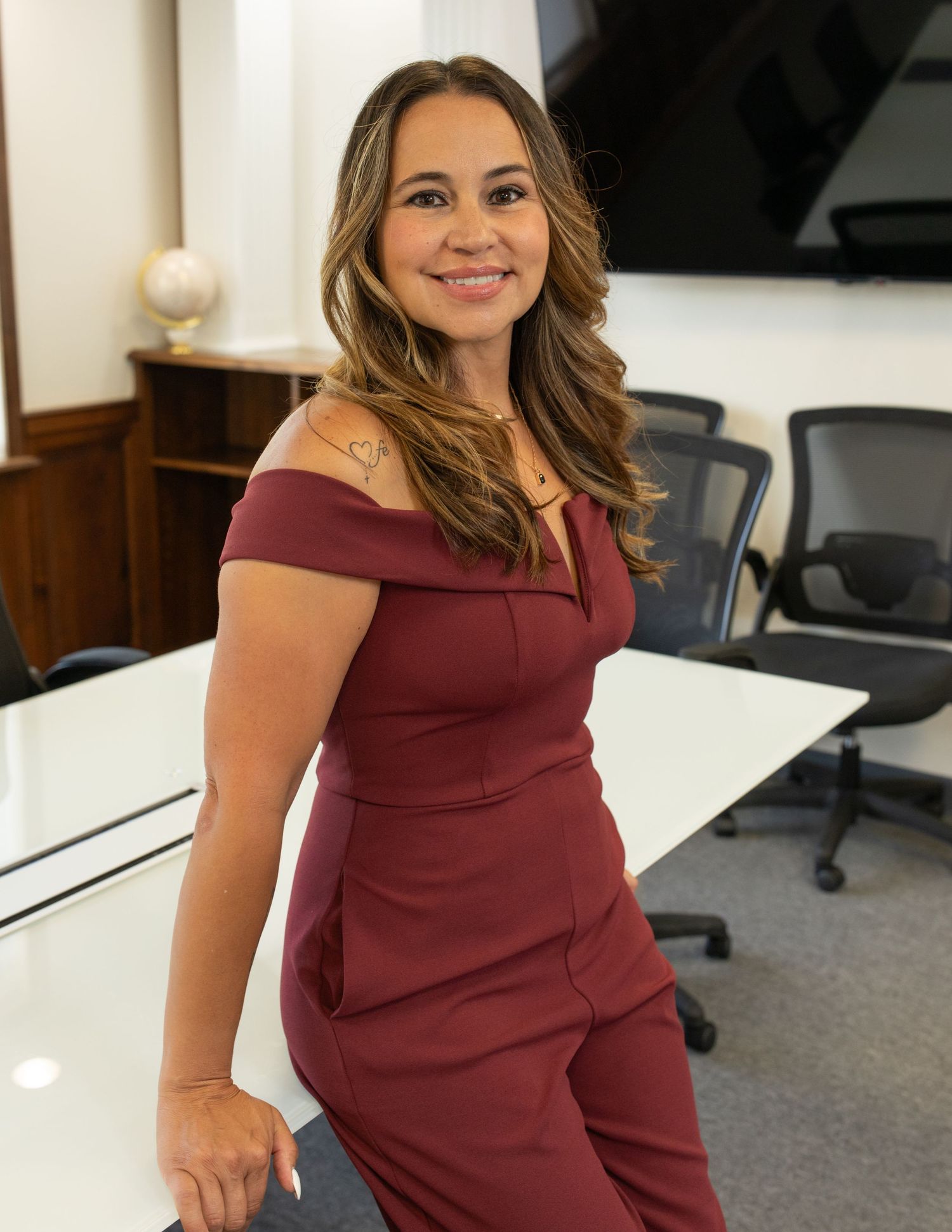 Professional in burgundy dress working in modern office environment.