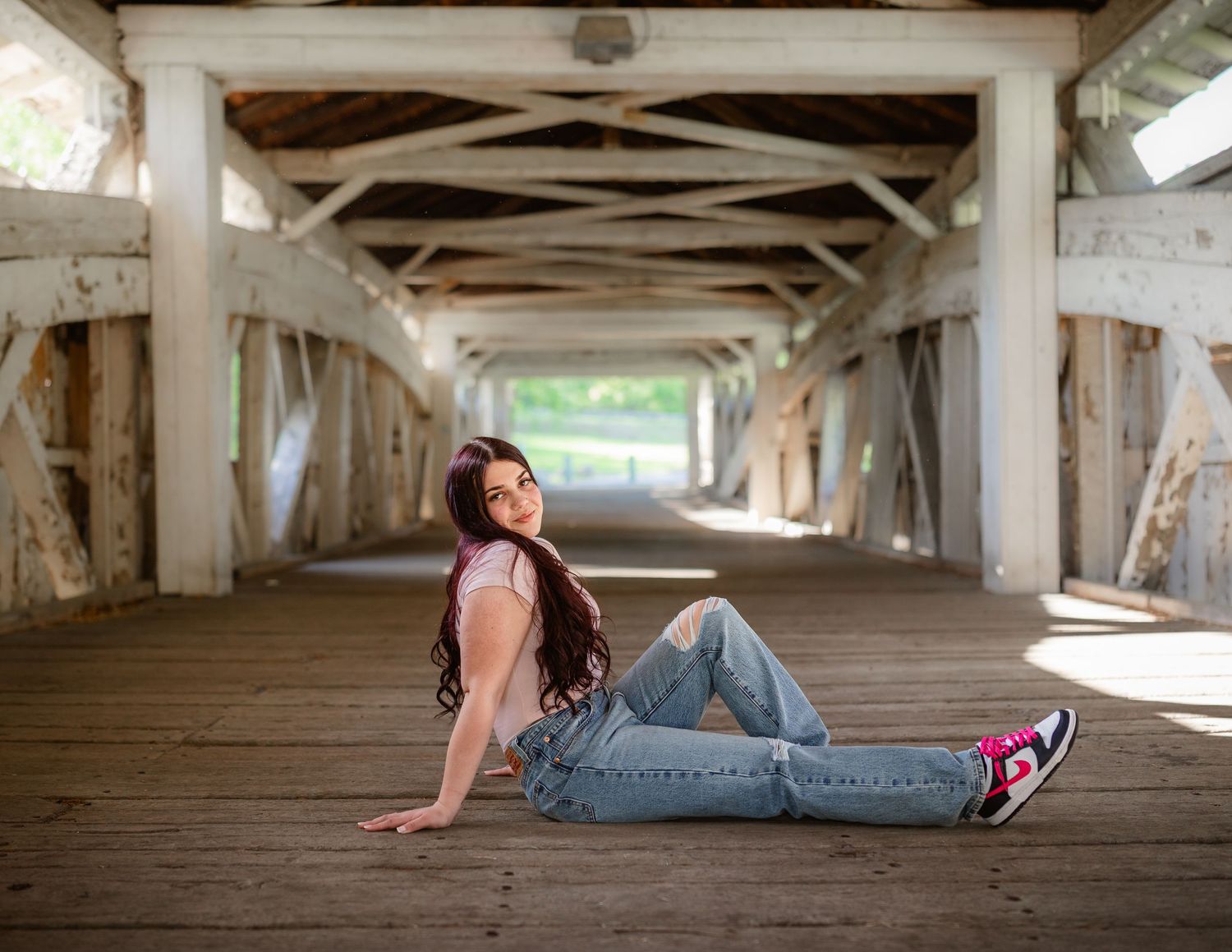 A person lies on a wooden floor under a bridge or pier structure in an artistic photo series.