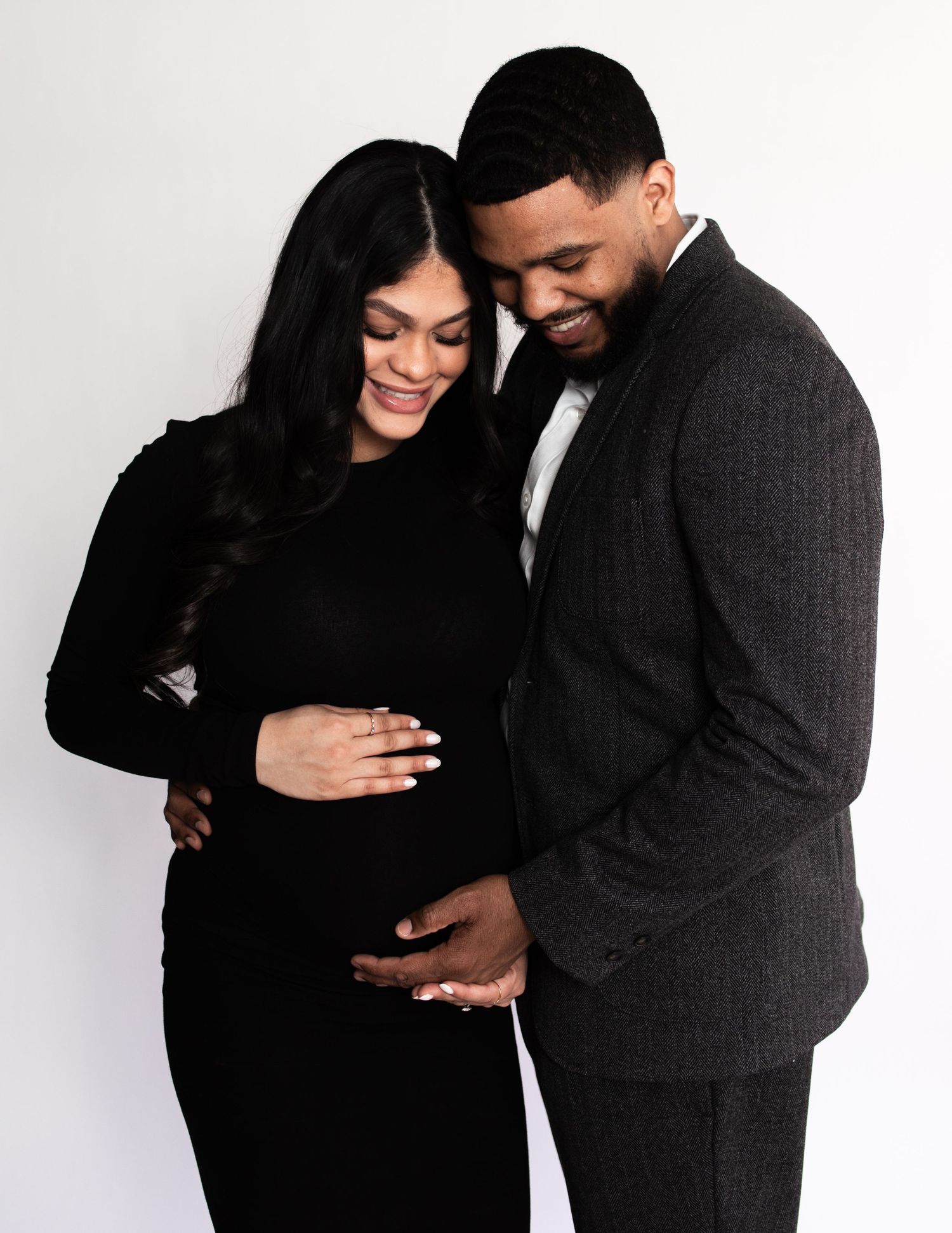 Expectant couple sharing intimate moment during studio maternity session.