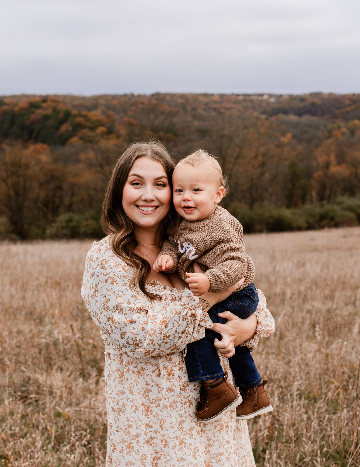 Family enjoying tender moments together in an autumn field with fall foliage.