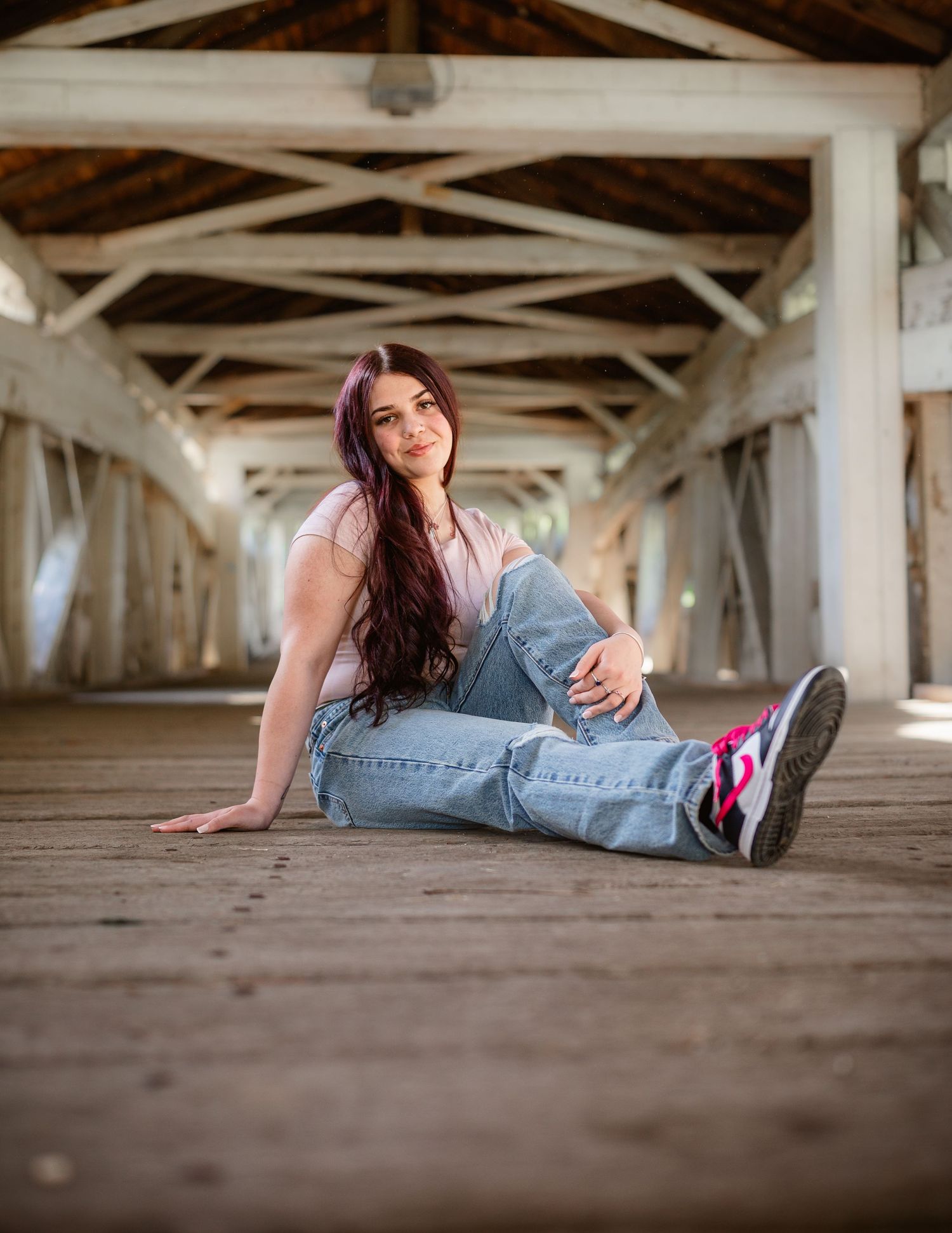 Creative graduation photos taken lying down under wooden bridge or deck structure.