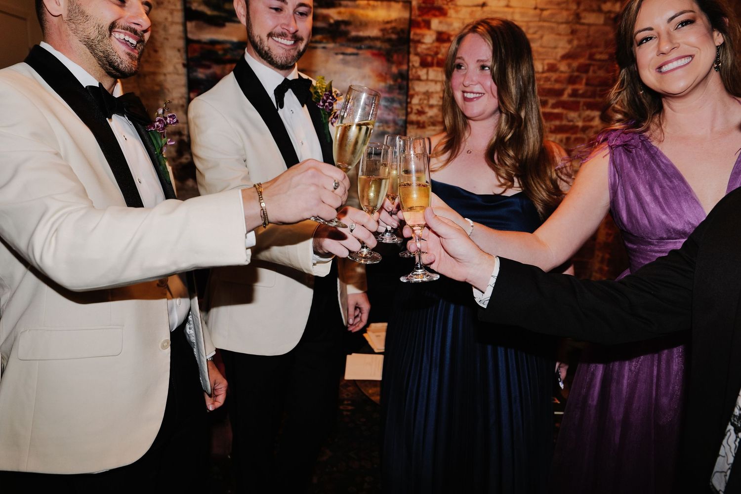 Wedding party members toasting and celebrating with drinks at reception.