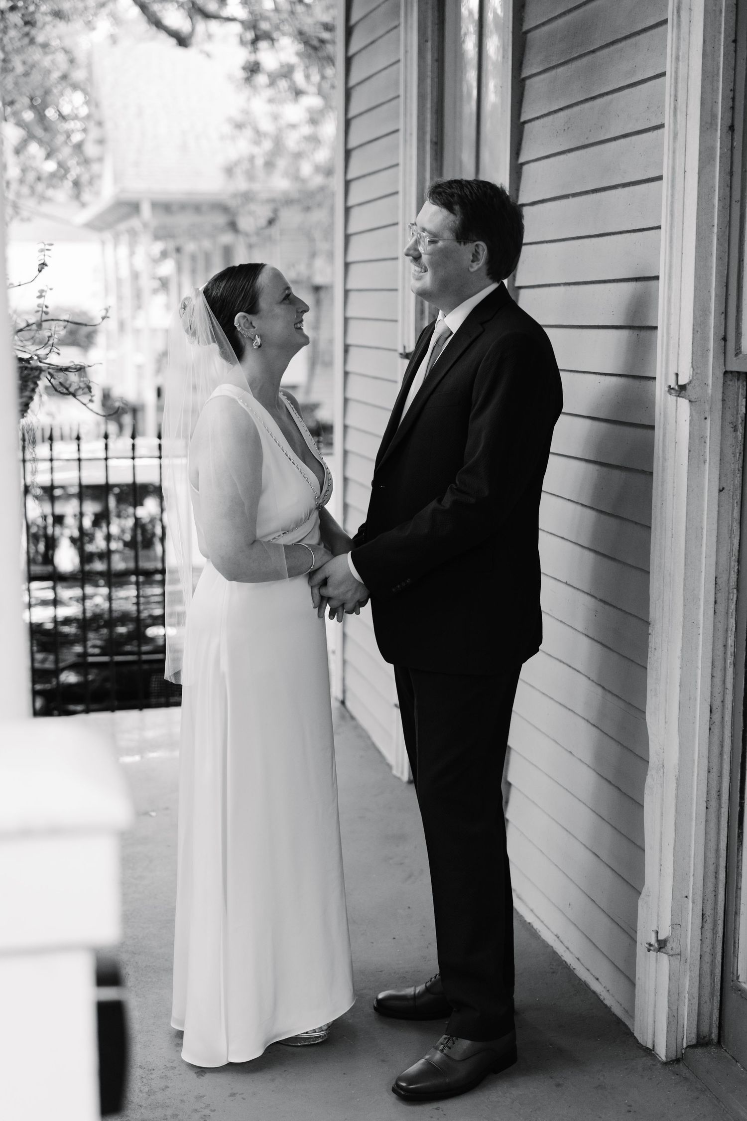 Black and white photo of a couple standing on a covered porch of a white clapboard building.