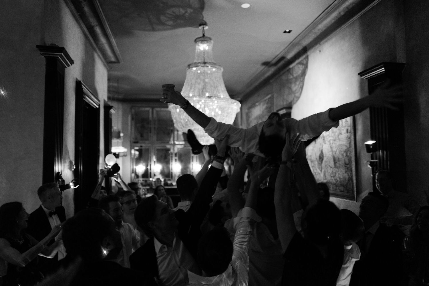 Dark atmospheric reception hall with chandelier lighting and silhouetted guests.