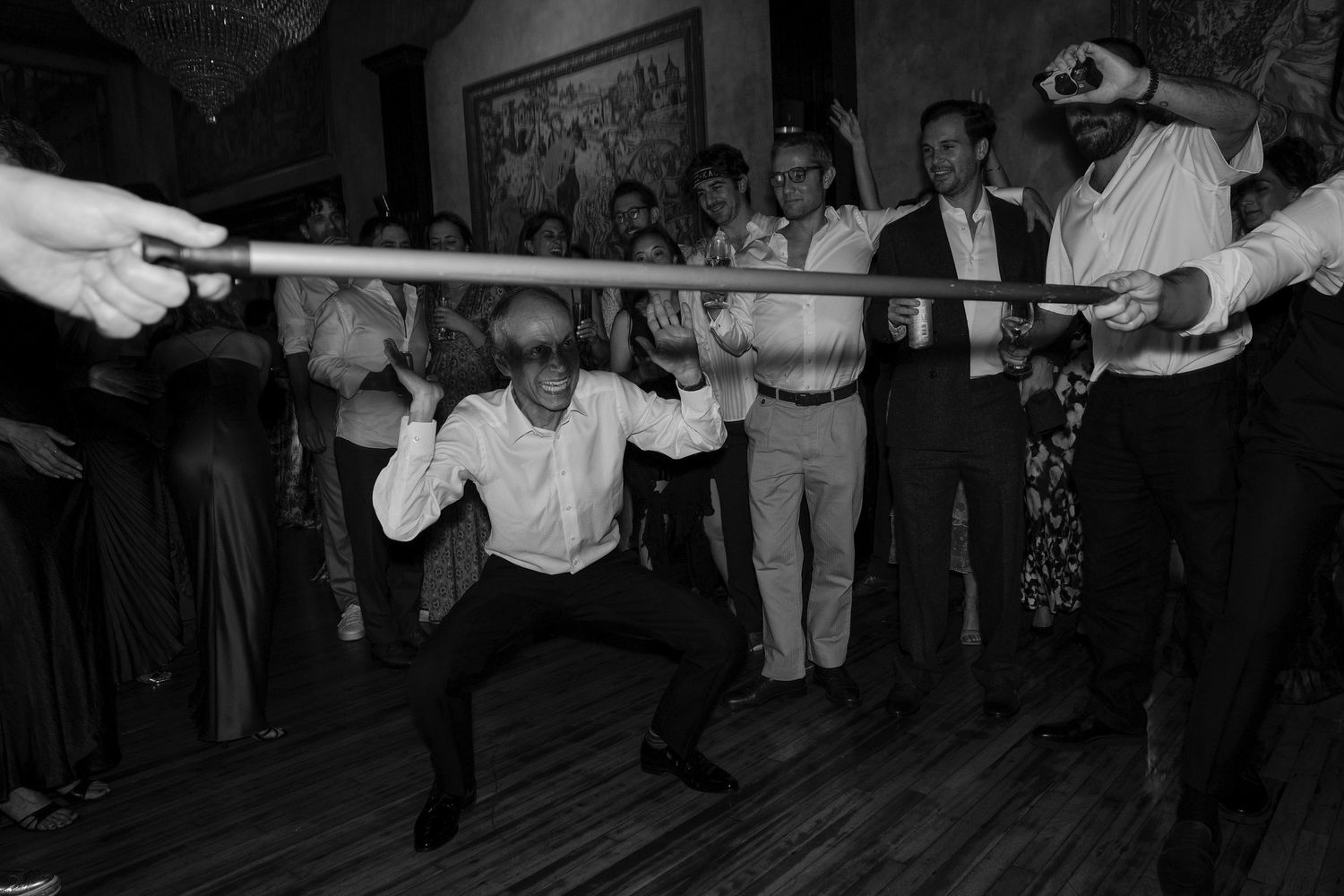 Wedding reception guests dancing in a dark room with dramatic lighting.