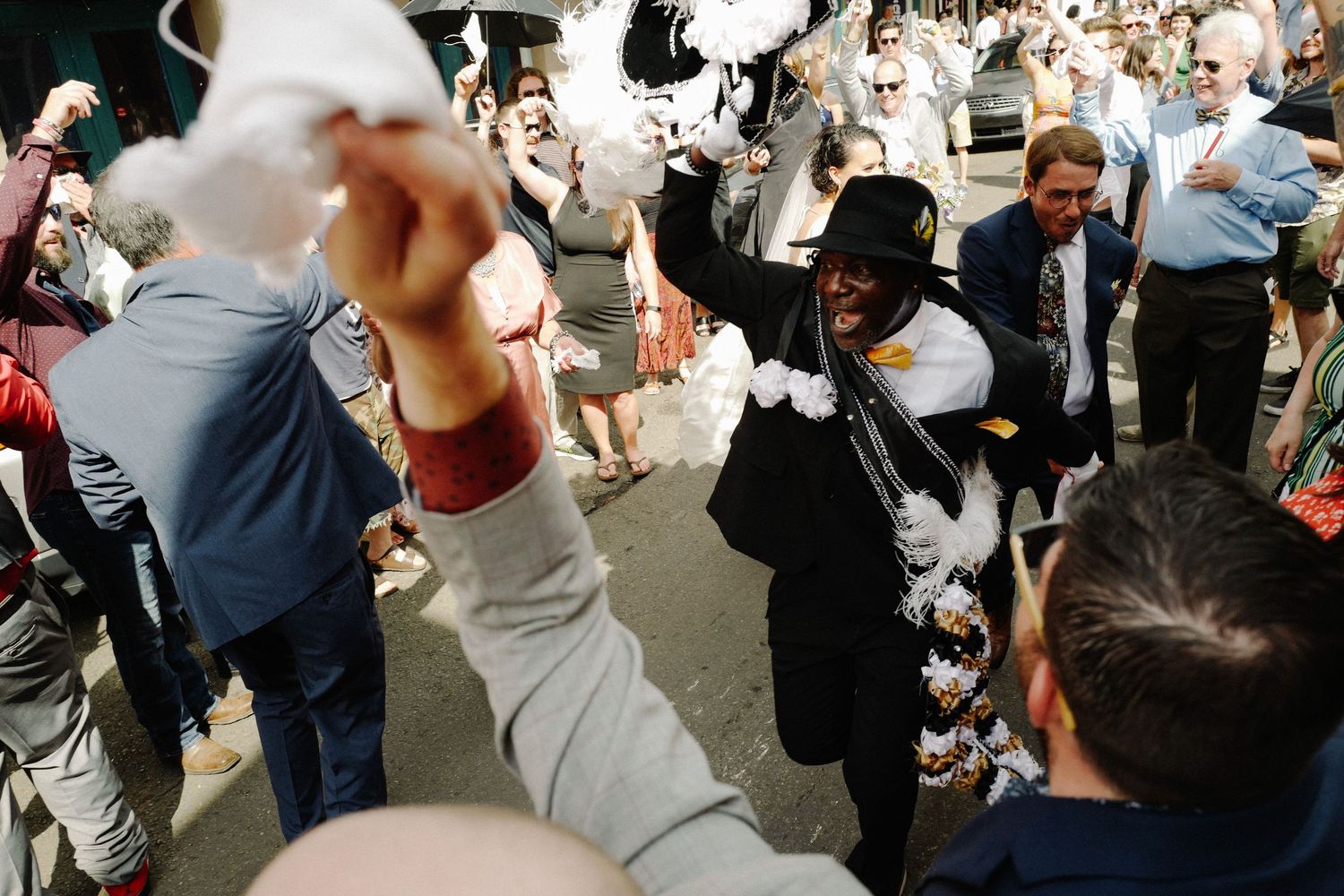 Aerial view of wedding guests celebrating at a New Orleans Second line with white parasols outdoors.