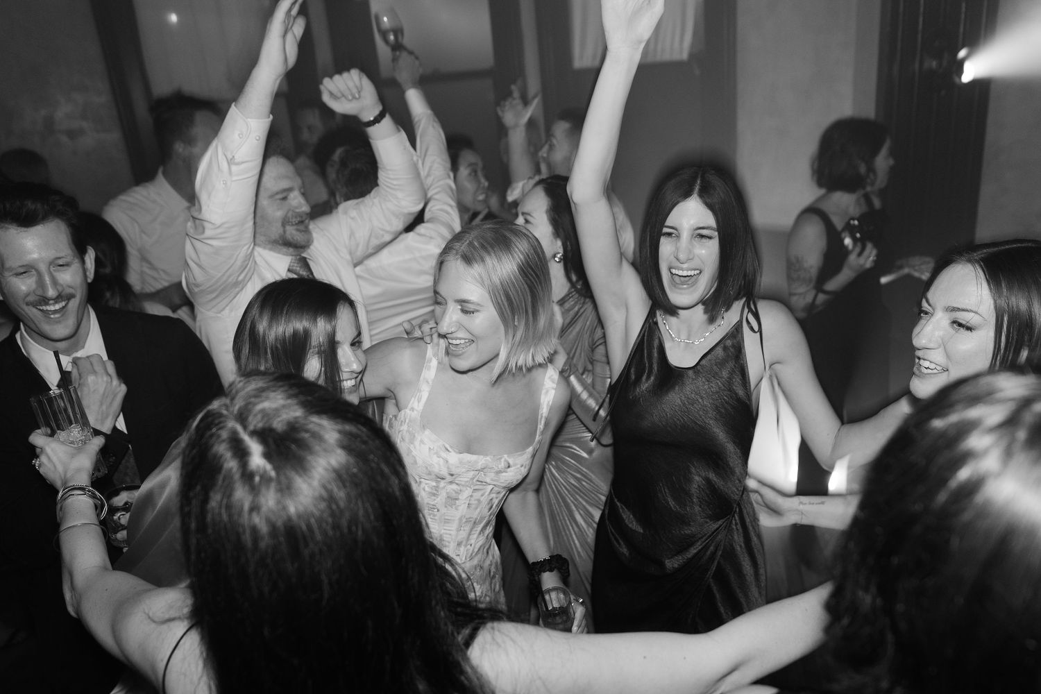Black and white photo of energetic dancing at a wedding reception.