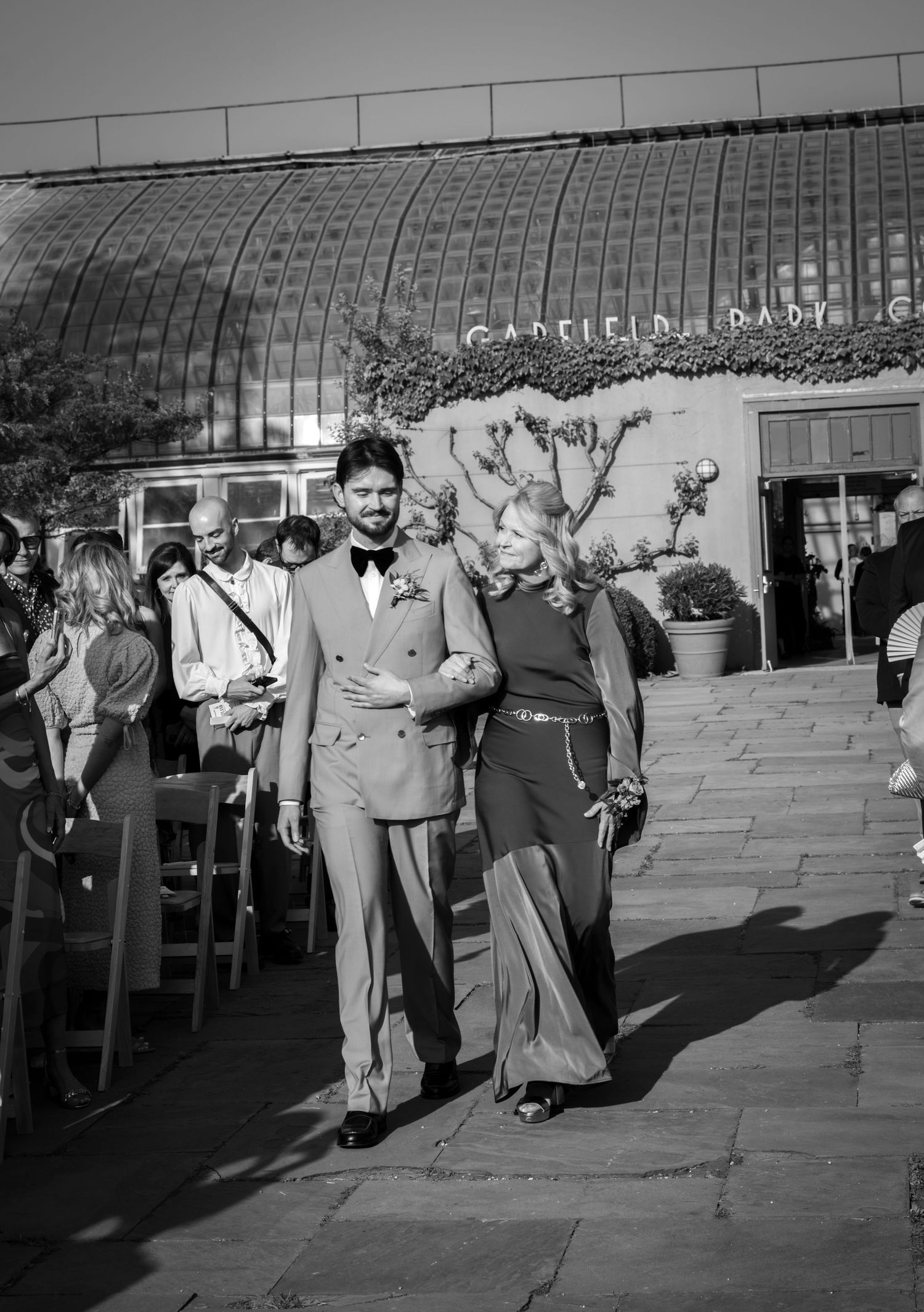 Groom and his mother walk down the aisle outdoors, film wedding photography by Palm Meadow Weddings New Orleans