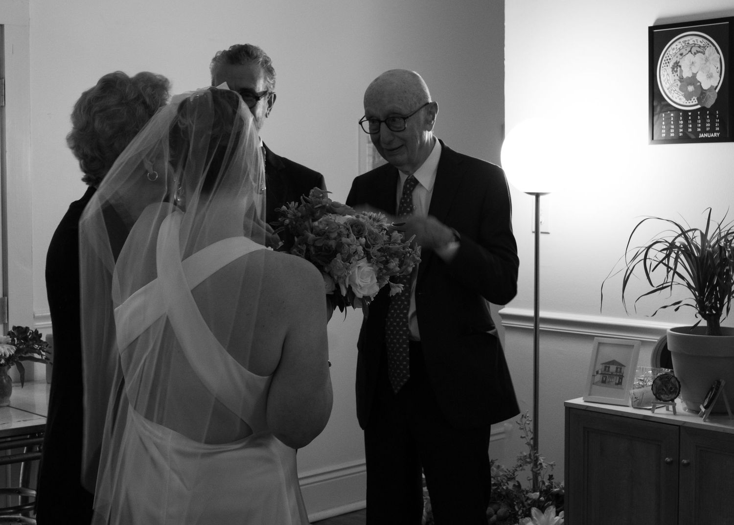 Black and white interior wedding scene with dramatic lighting and silhouettes.