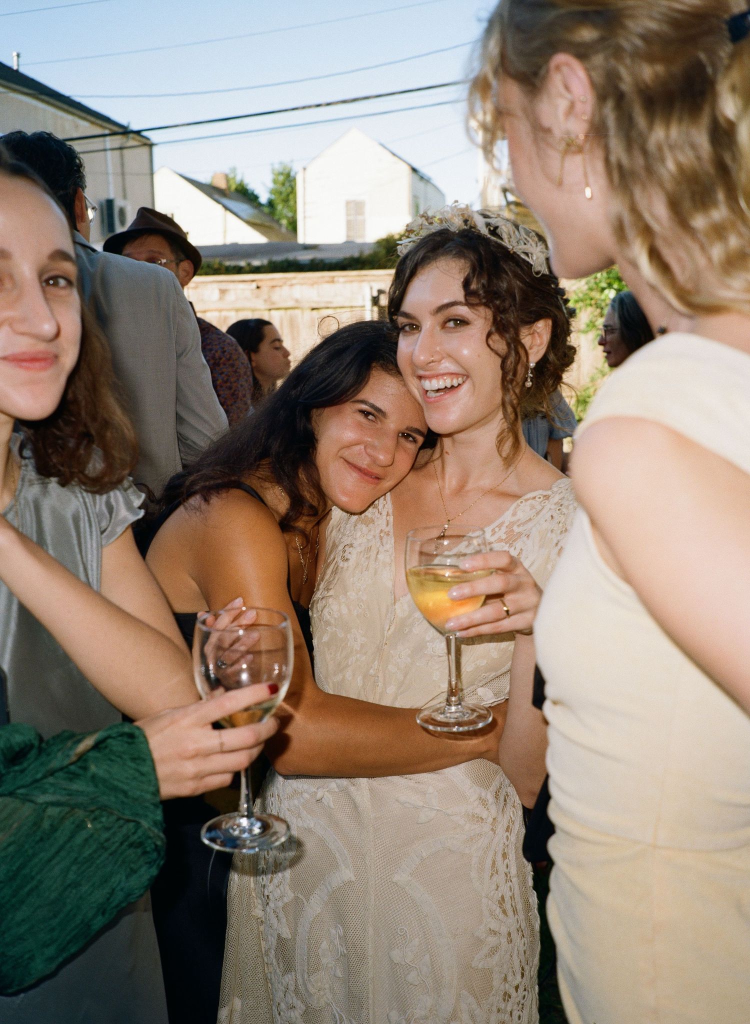Bride and bridesmaids enjoying drinks and conversation at an outdoor celebration.