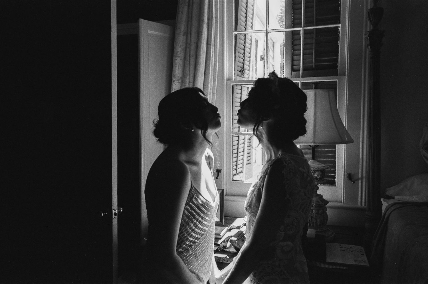 Silhouetted figures in window light creating dramatic wedding portraits.