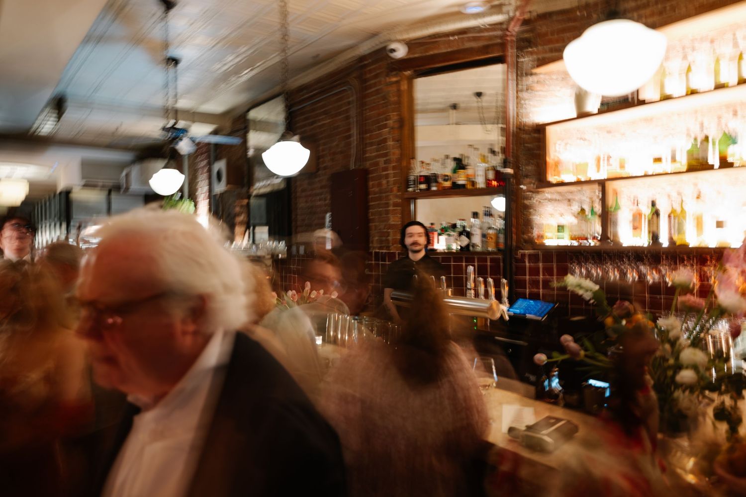 Dimly lit bar interior of a wedding after party with glowing lights and bottles creating an atmospheric ambiance.