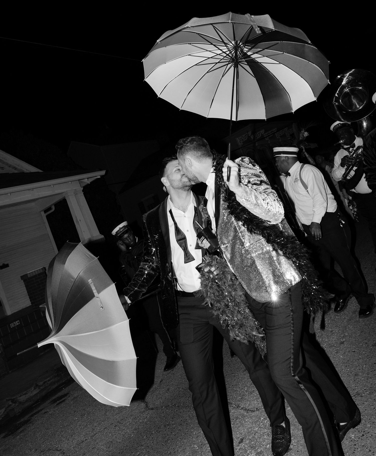 Grooms kiss during a New Orleans second line after a wedding.
