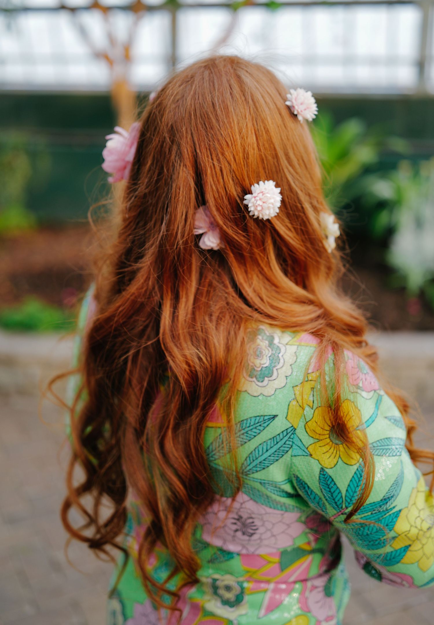 Red hair adorned with a flower clip against floral print fabric.