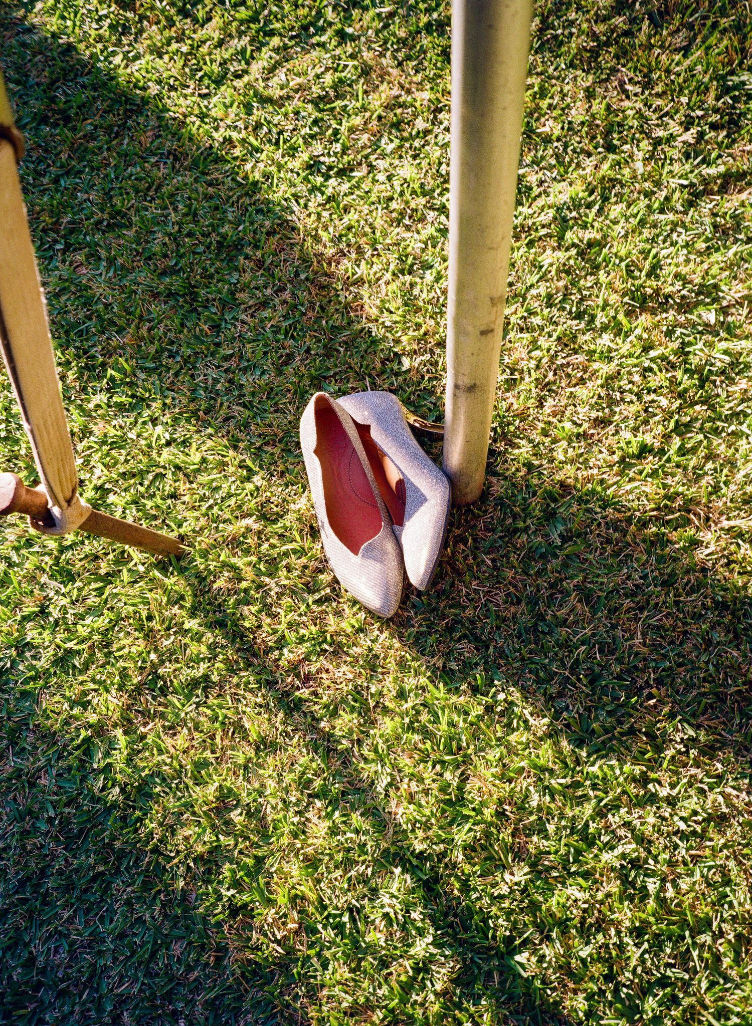 Shadows cast on grass from people standing in bright sunlight at an outdoor event.
