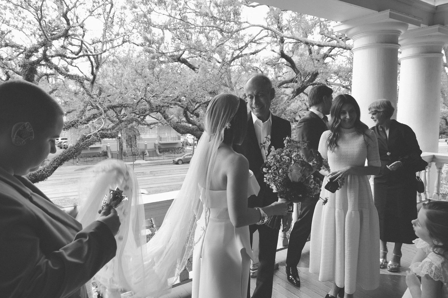 Wedding ceremony taking place on a covered porch surrounded by trees.