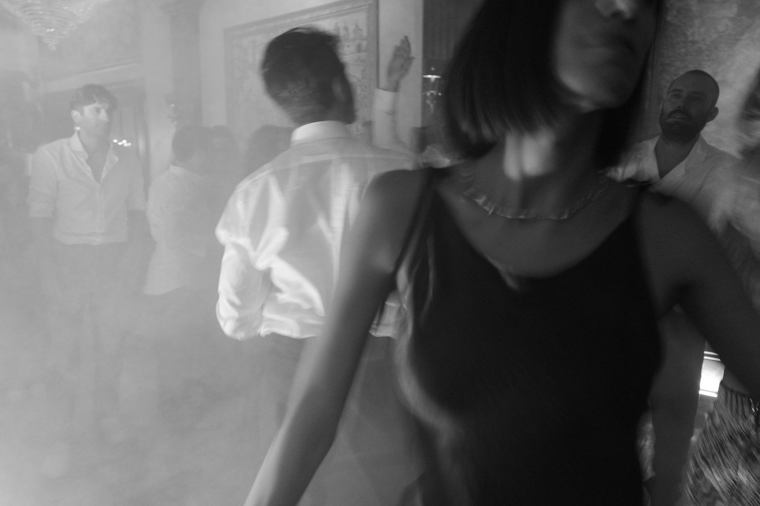 Black and white candid shots of wedding guests dancing and celebrating in a dimly lit venue.