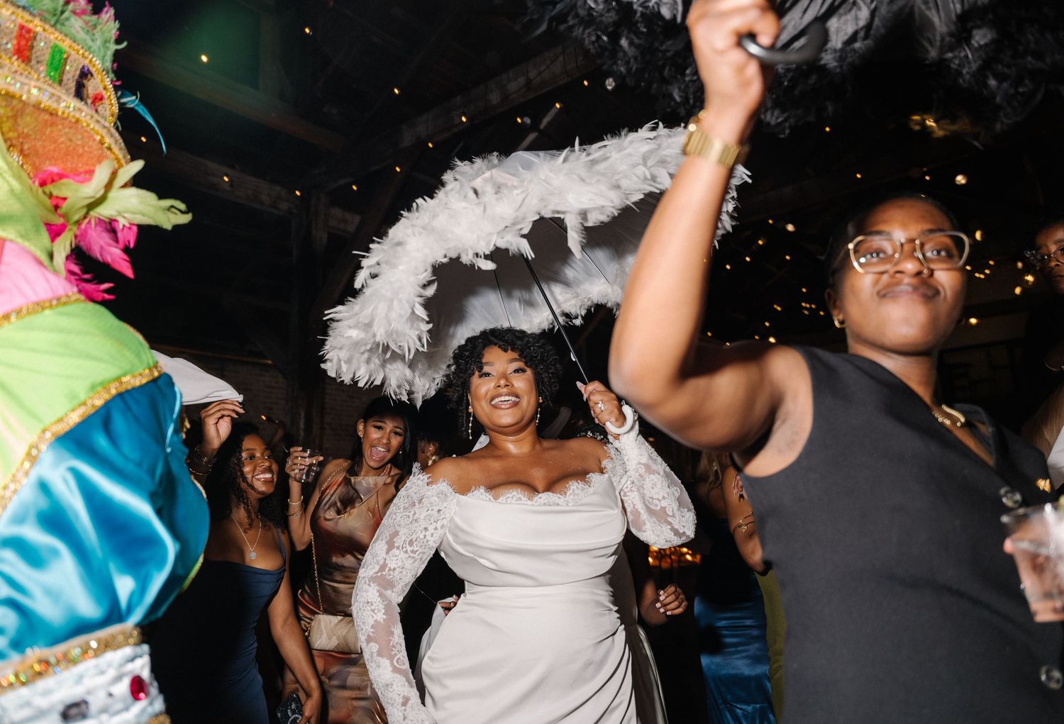 Bride in white lace dress dances joyfully with guests at a vibrant New Orleans-style wedding reception.