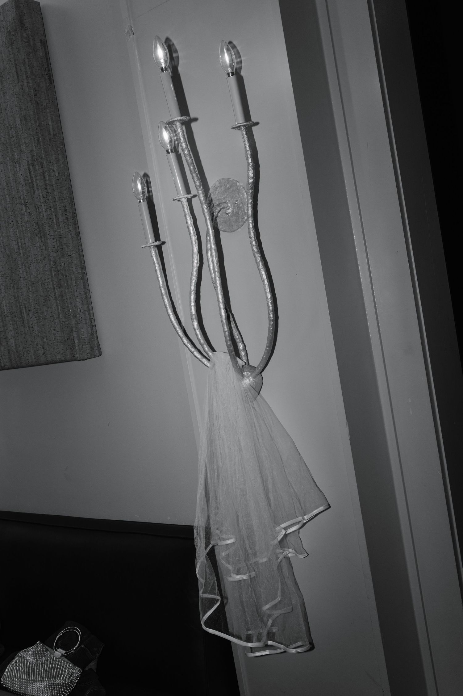 A wedding dress hangs elegantly against a light background with wall sconces.
