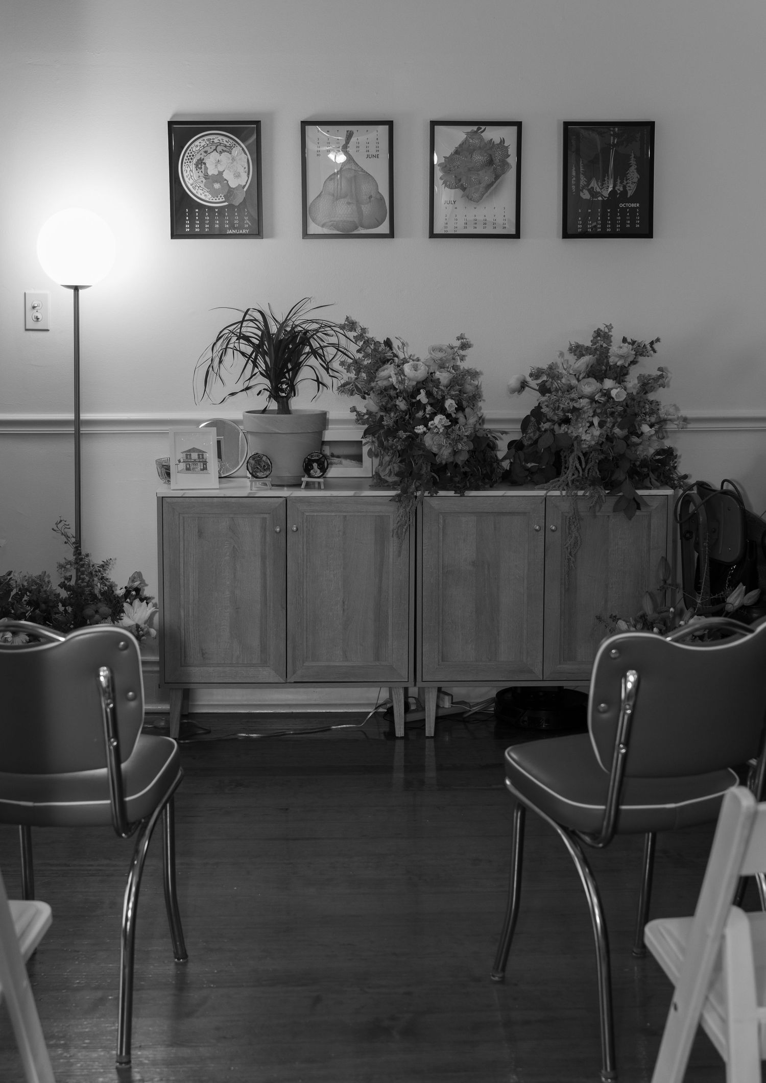 Altar with wooden cabinets and chairs arranged along wall under framed artwork.