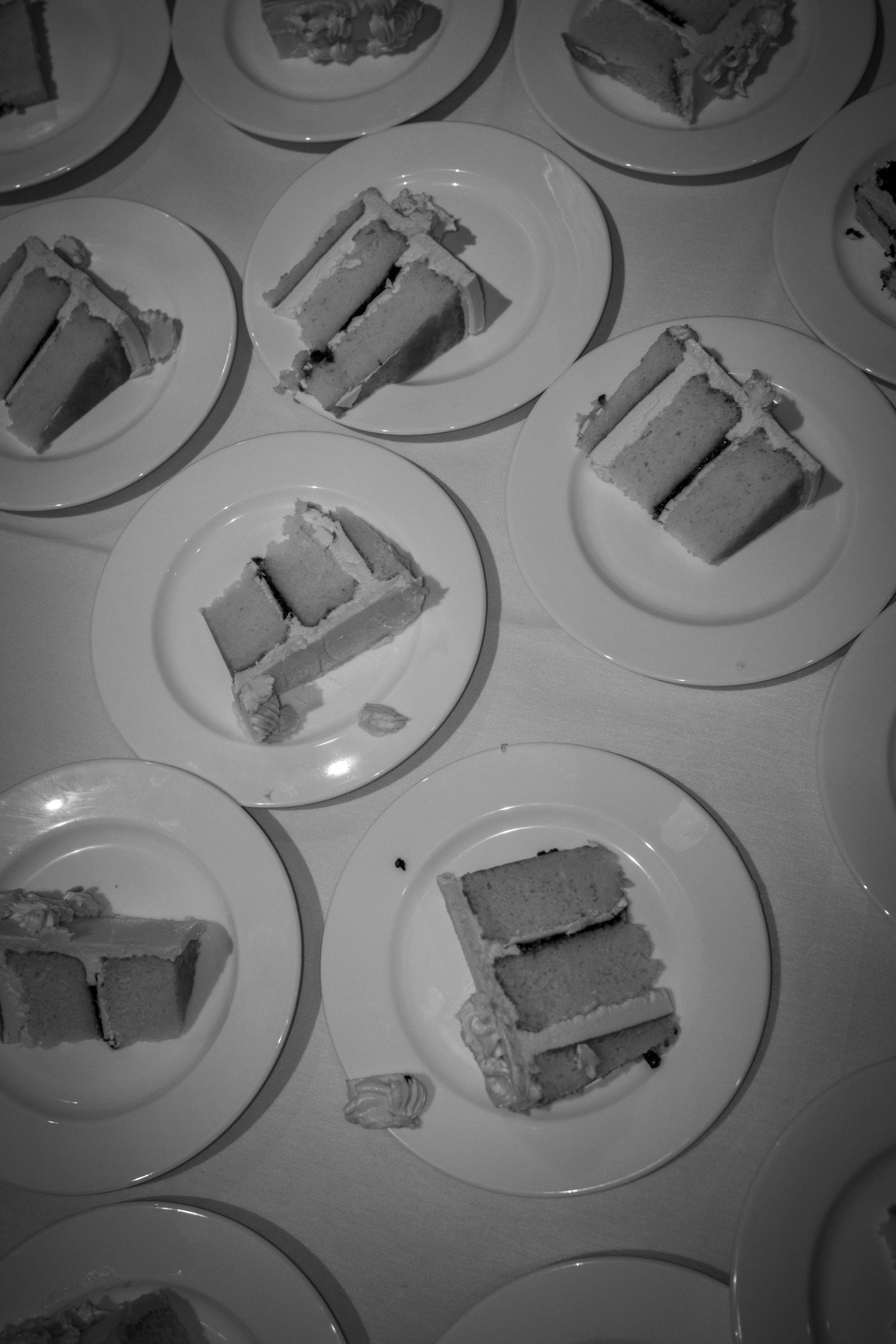 Multiple plates of wedding cake slices arranged on white dishes.