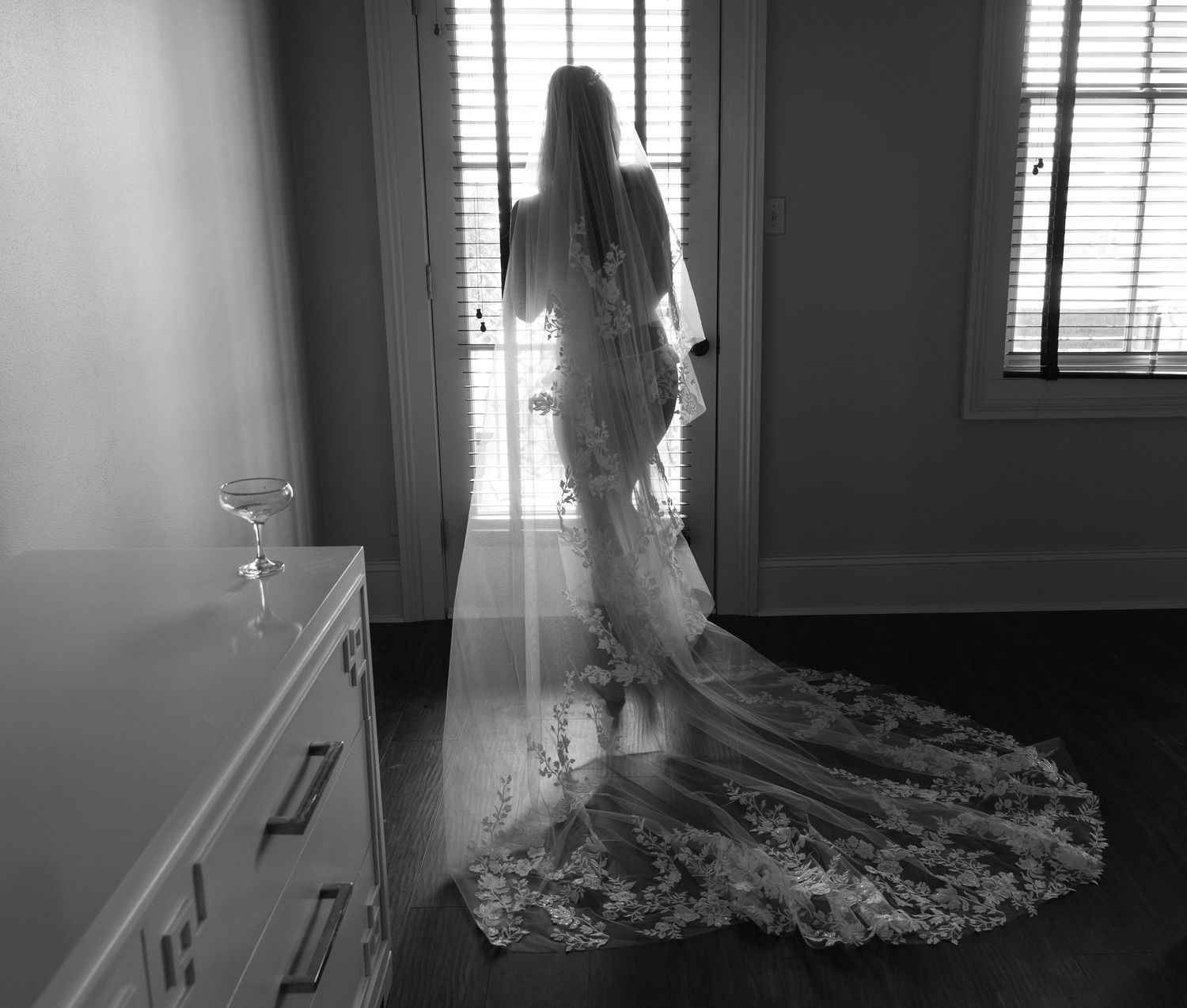 Dramatic window lighting creates silhouettesof a bride's veil in an elegant interior space.