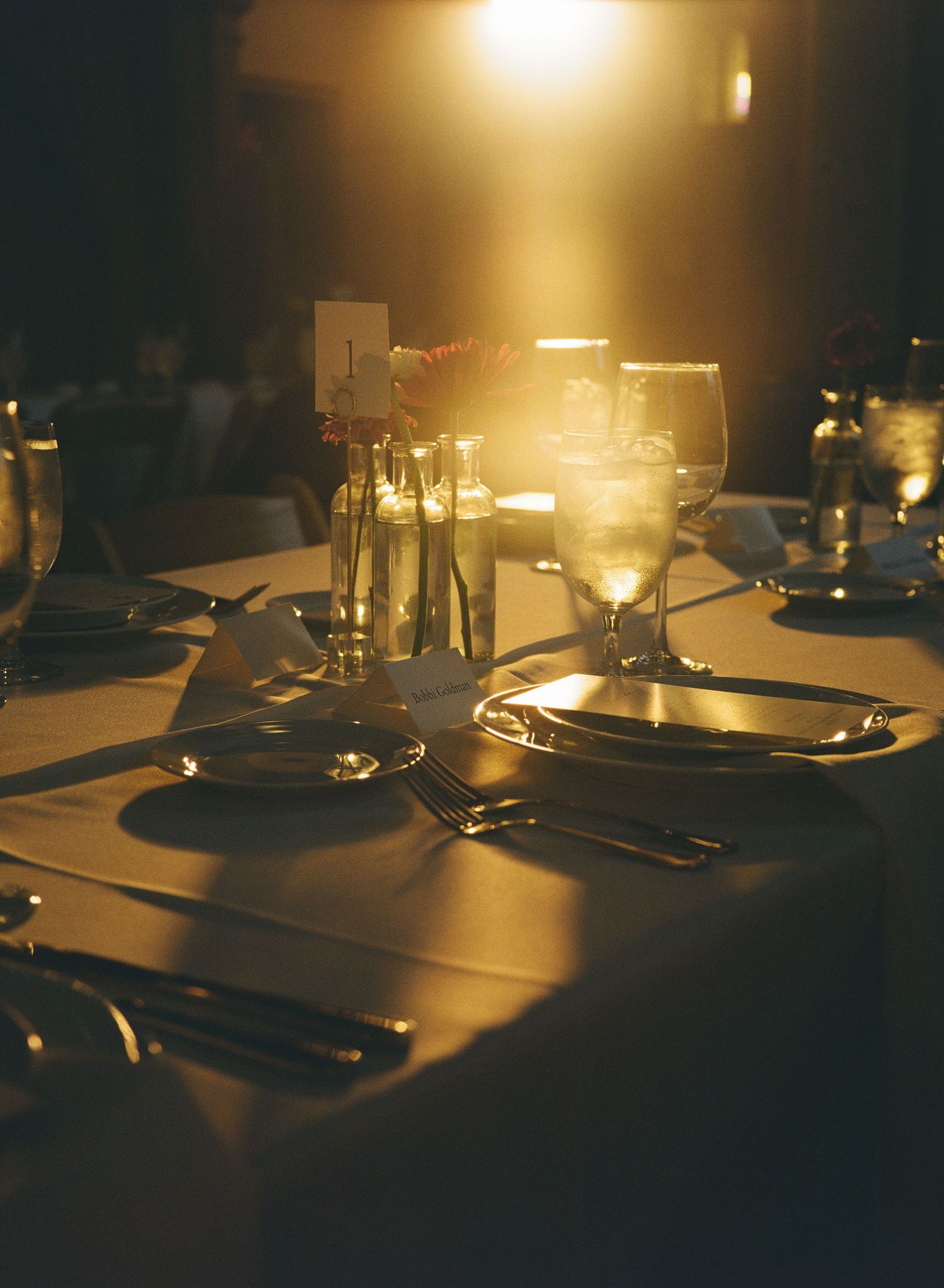 Intimate dinner table setting at a wedding reception with warm ambient lighting and place settings.